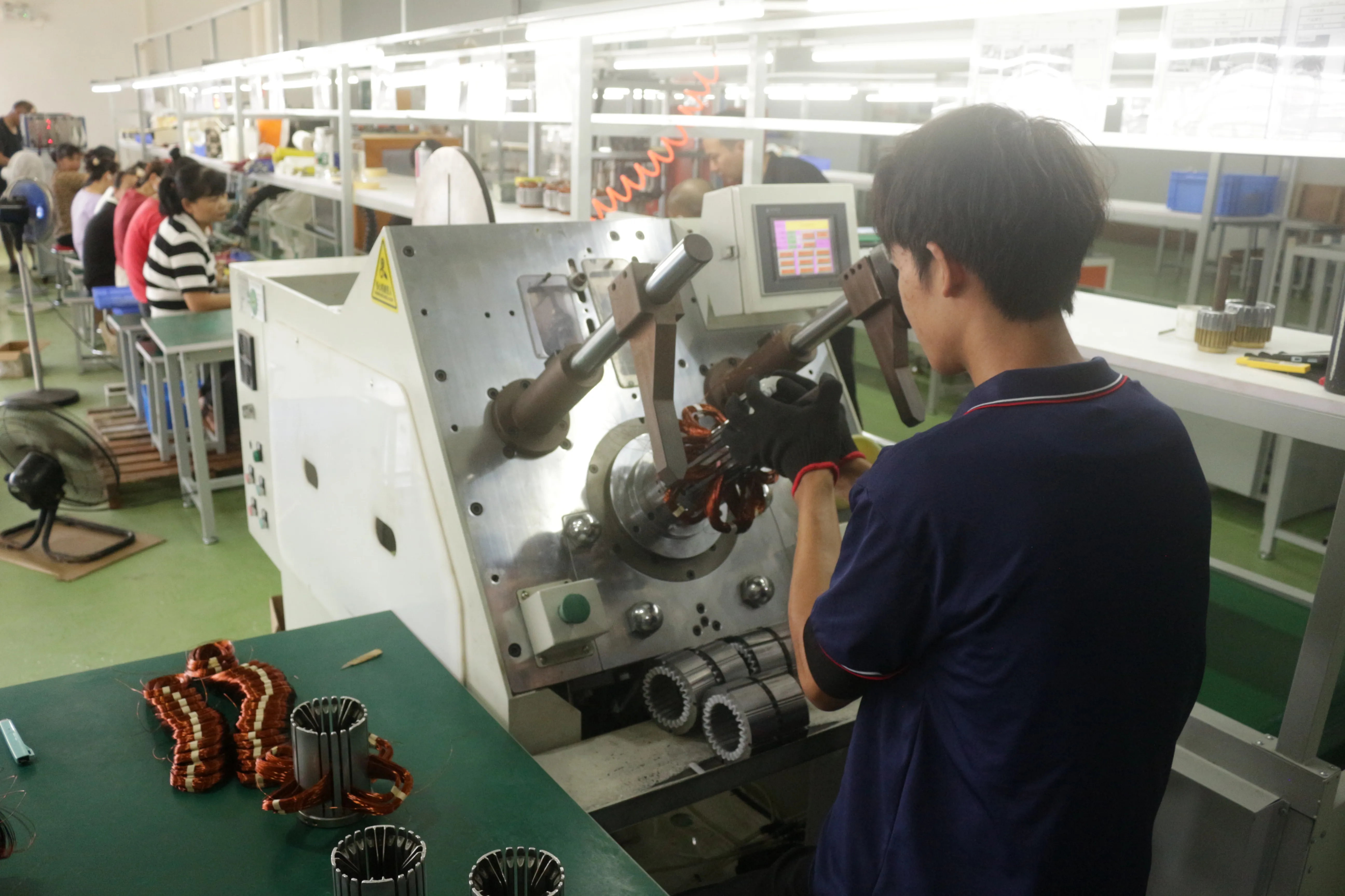 Technicians performing motor coil winding process at HUANGXI factory